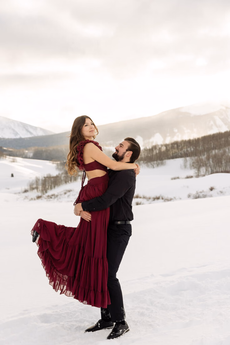 Crested Butte proposal pricing client review. Engagement couple with woman wearing a red dress and man wearing black lifting her. for Proposal Packages
